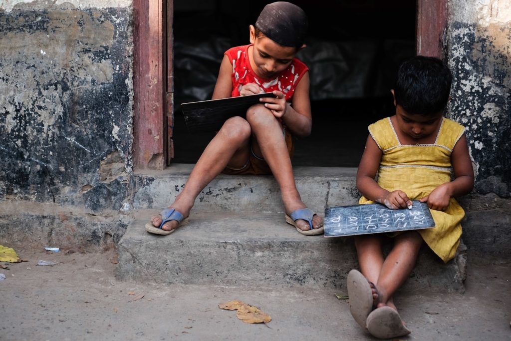 Students on street learning alphabet with chalk boards in India