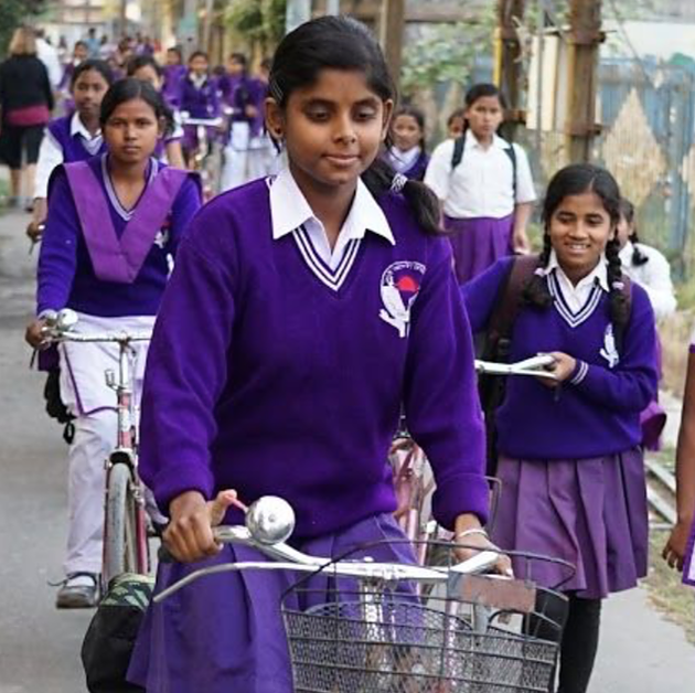 School children in purple uniforms coming home from school in India