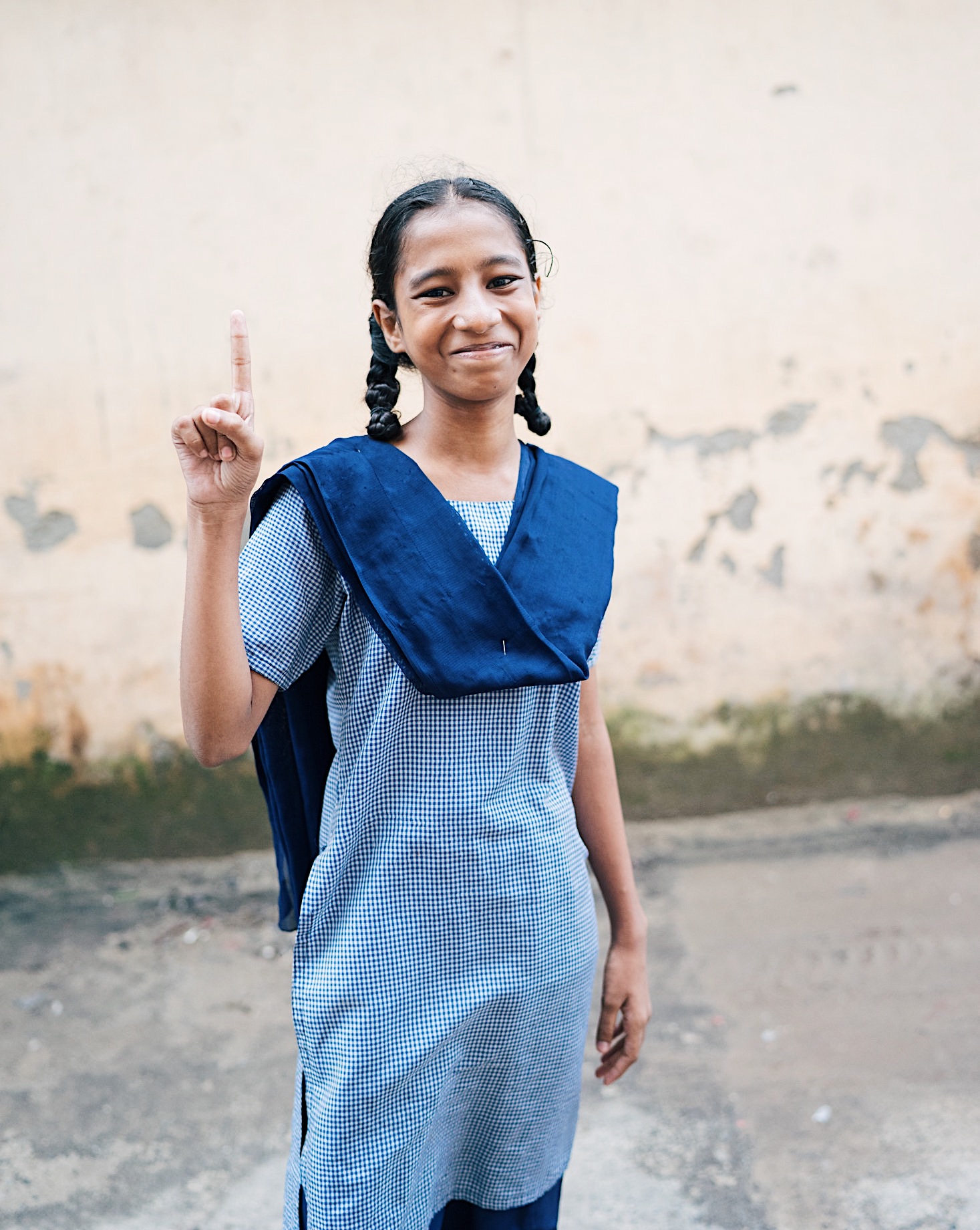 Girl student in blue uniform with 1 finger up representing education is empowerment